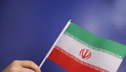 فوتیج پرچم ایران در دست روی پس زمینه آبی
