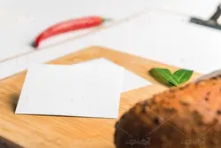 موکاپ برگه روی تخته شاسی در کنار نان فانتزی و فلفل  روی میز