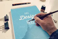 موکاپ دفترچه طراحی همراه با قلم و خودکار با دوربین عکاسی