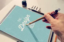 موکاپ دفترچه طراحی همراه با قلم و خودکار با دوربین عکاسی