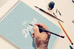 موکاپ دفترچه طراحی همراه با قلم و خودکار با دوربین عکاسی