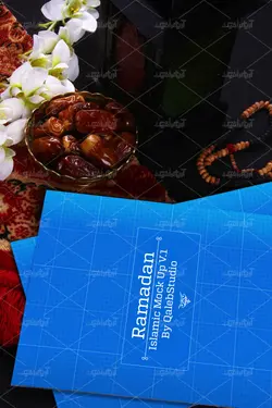 موکاپ پوشه و دفترچه روی میز و ظرف خرما کنار فانوس