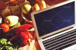 موکاپ لبتاب و دفترچه روی میز و پس زمینه آشپزخانه