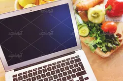 موکاپ لبتاب و دفترچه روی میز و پس زمینه آشپزخانه