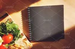 موکاپ لبتاب و دفترچه روی میز و پس زمینه آشپزخانه