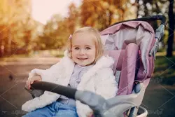 دانلود عکس با کیفیت دختر بچه نوزاد در کالسکه با چهره خندان